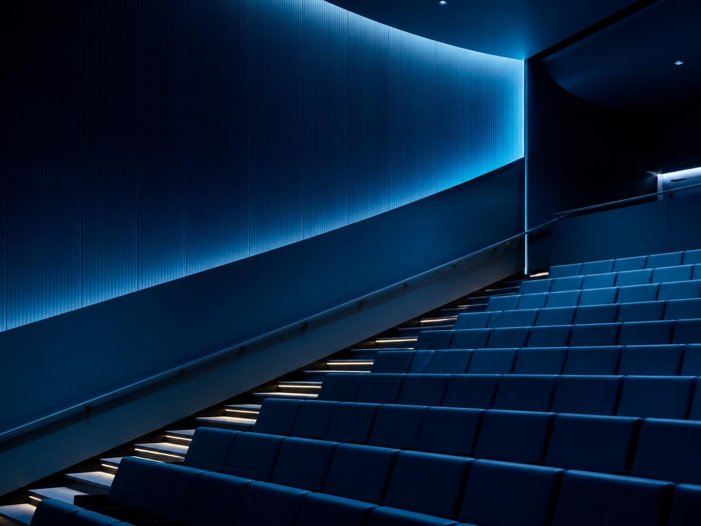 Abstract view of an empty modern auditorium lit in deep navy and teal.